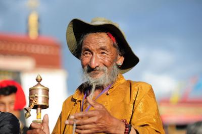 Elderly Tibetan man holding a prayer wheel