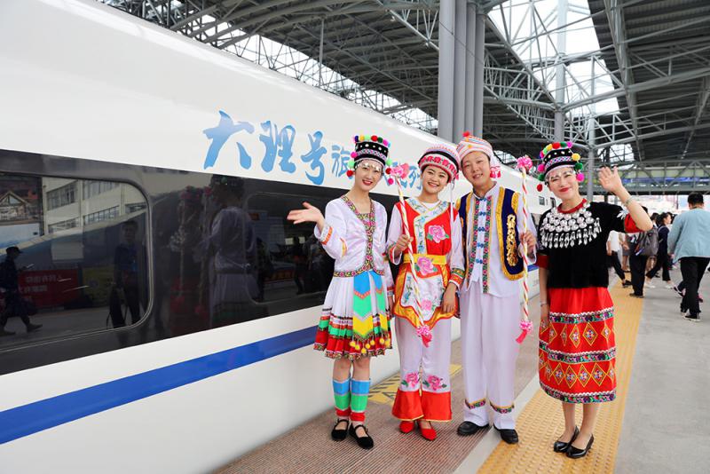 The Local People in Traditional Costumes Poses for a Group Photo by the New Kunming - Dali High-speed Train