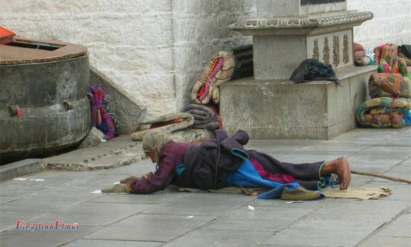 An old Tibetan woman pray before Jokhang Temple