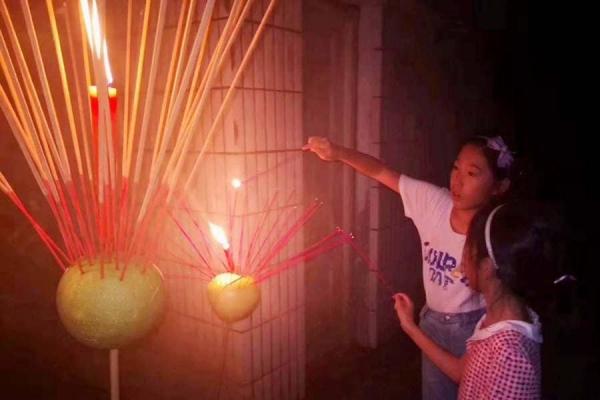 children insert incense sticks on pomelos