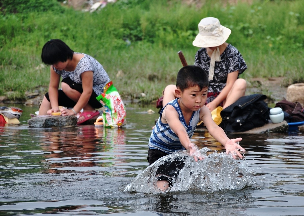 village women washing clothes beside Yulong River